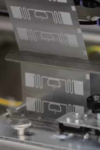 Close-up of RFID inlays being processed through a precision manufacturing machine within an industrial production environment
