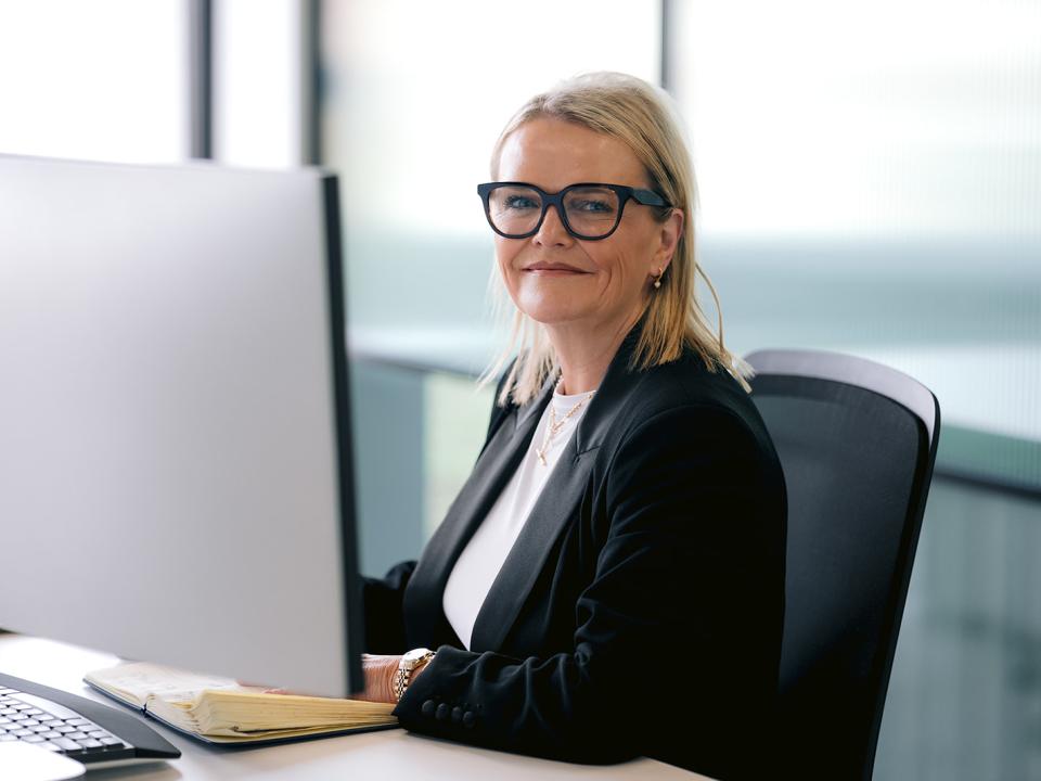 Lady wearing glasses smiling at desk