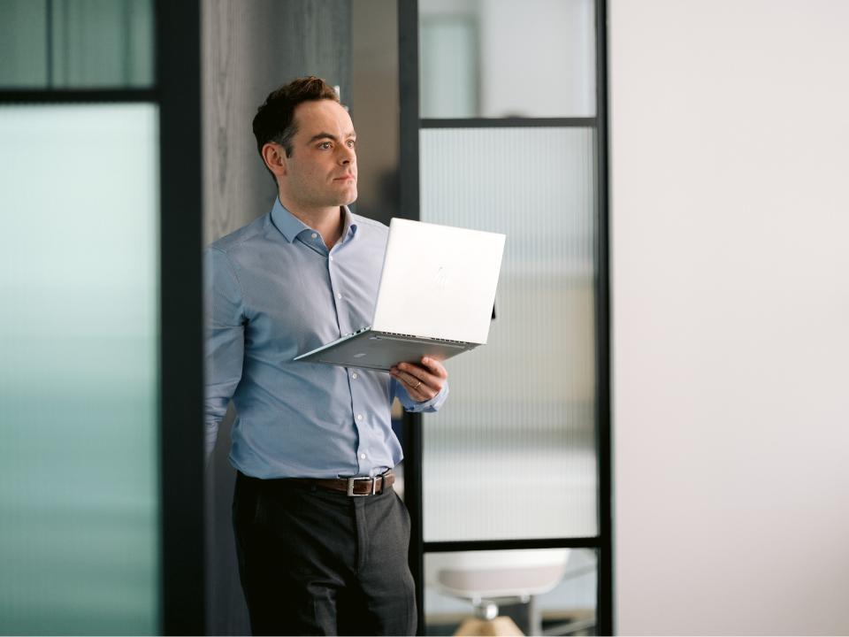 Grenadier Holdings employee holding a laptop in the office.