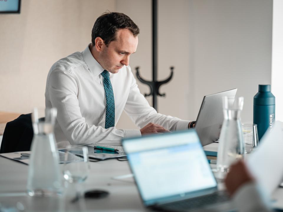 Legal Counsel reviewing documents during a meeting at Grenadier Holdings.