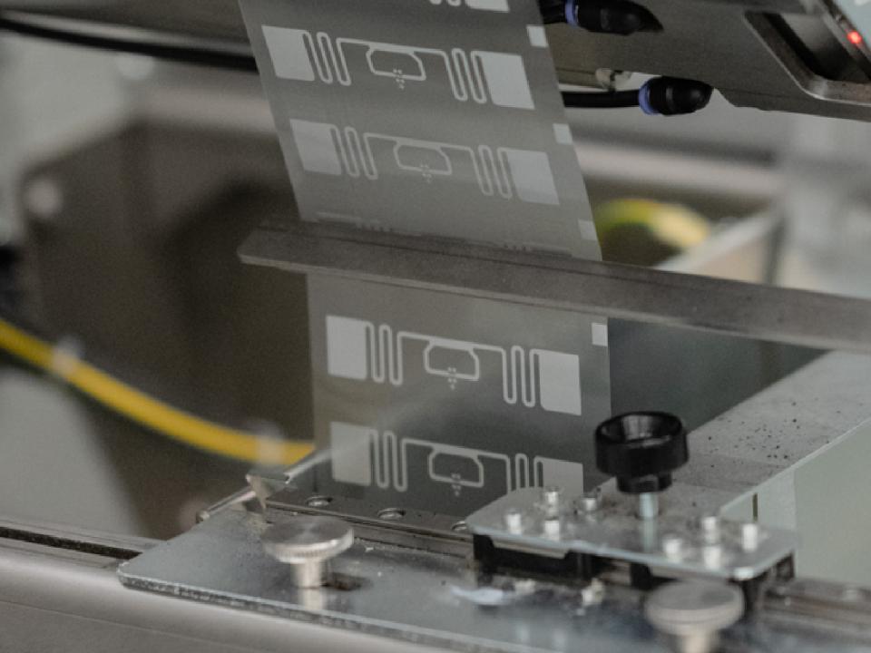 Close-up of RFID inlays being processed through a precision manufacturing machine within an industrial production environment