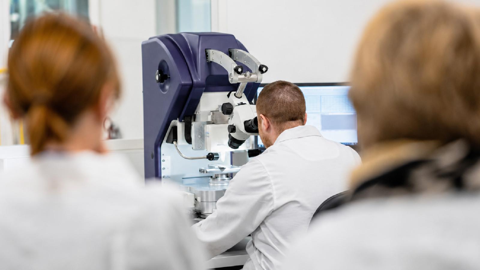 Quality control technician performing microscopic inspection in a modern laboratory, supporting precision manufacturing and advanced production processes.